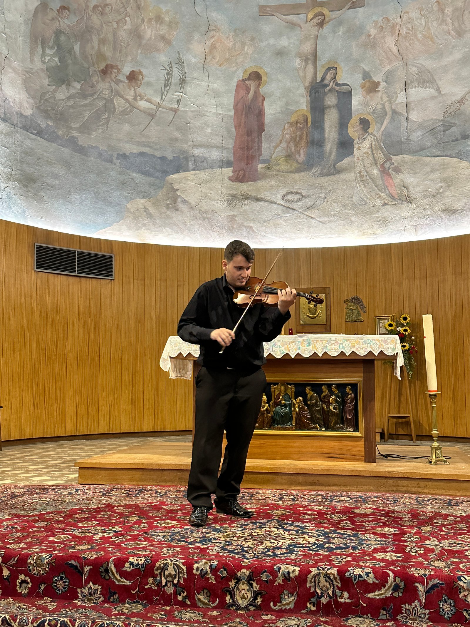 Glenn Zuili jouant du violon dans l'église, sous la fresque